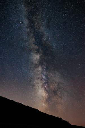 The Milky Way and silhouette of the hill. Starry night background vertical photo.の写真素材