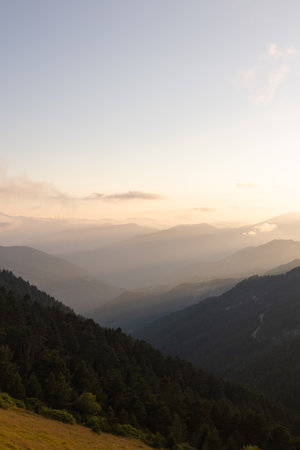 Layered mountains with haze at sunset. Landscape background vertical photo. Mountain range.の写真素材