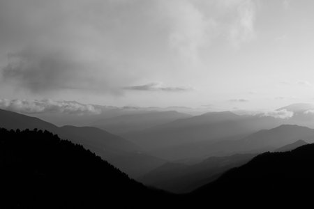 Black and white landscape of the mountain range with haze at sunset. Layered mountains landscape.