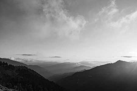 Landscape of the mountain range at sunset with mist. Black and white landscape photo.