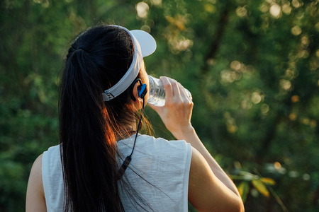 Woman runner drinks water after running.の写真素材