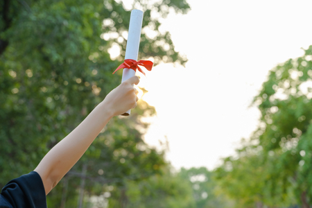 Female university graduate celebrates graduation ceremony receiving degree certificate happily with excitement.の写真素材