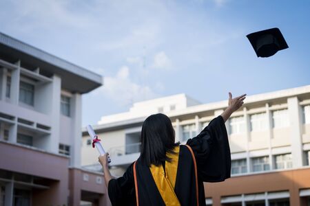 Portrait of happy and excited of young Asian female university graduate wears graduation gown and hat celebrates with degree in university campus in the commencement day. Education concept.の写真素材
