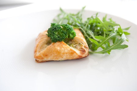 Vegetarian pastry with cheese and broccoli on a white plateの写真素材