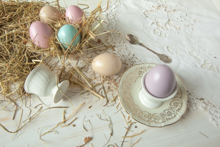 Stack of colorful easter eggs on straw with wooden table backgroundの写真素材