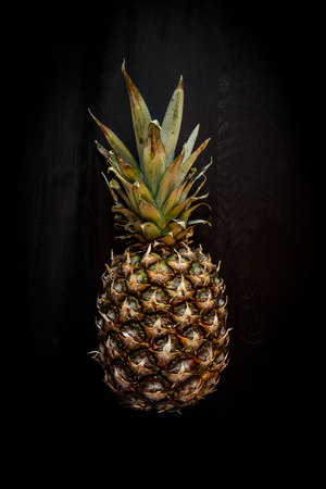 Pineapple isolated on black wood background, ananas tropical fruitの写真素材