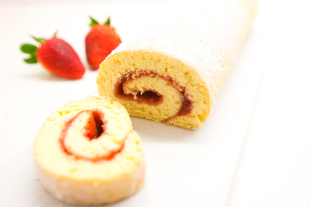 Swiss roll with strawberry jam on a white table