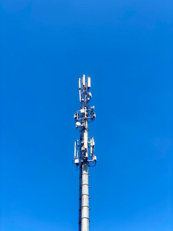 Cell tower, blue sky background. 3g, 4g, 5g. Mobile communications, various data transmission systems are installed on one tower. Modern technologies for information transmission. Vertical photo.の写真素材