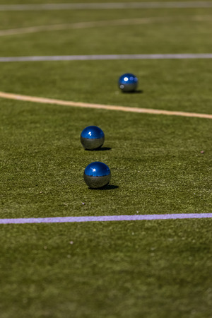 Petanque is a form of boules where the goal is to toss or roll hollow steel balls as close as possible to a small wooden ball called a jack, while standing inside a circle with Both Feet on the Groundの写真素材