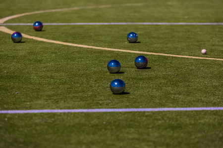 Petanque is a form of boules where the goal is to toss or roll hollow steel balls as close as possible to a small wooden ball called a jack, while standing inside a circle with Both Feet on the Groundの写真素材