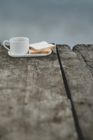 Breakfast set on wooden floor in the morning. Breakfast with coffee and bread.Do not focus on objects.の写真素材