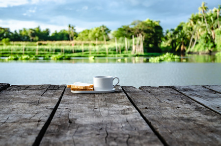 Breakfast set on wooden floor in the morning. Breakfast with coffee and bread.Do not focus on objects.の写真素材