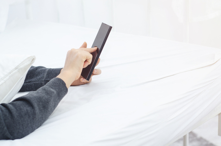 The black smartphone is in the hands of women.Lady holding phone.Pointing finger to mobile phone.The white room.の写真素材