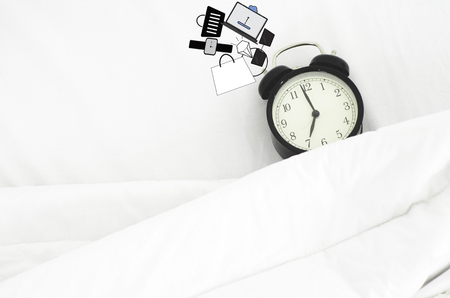 White bed In the bedroom And a black watch Put on a pillow.White Alarm Clock isolated Placed on a white background.Concept of spending time buying products.Do not focus on objects.の写真素材