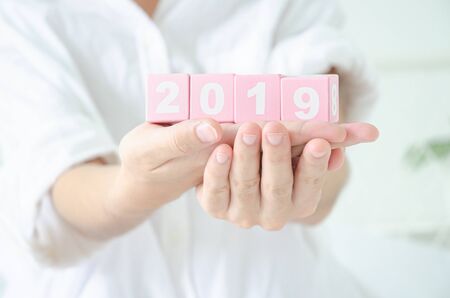 Small pink square wooden box with numbers in Asian women handsの写真素材