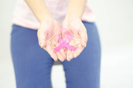 Pink ribbon in a woman's hand.Do not focus on objects.World Breast Cancer Day Concept.