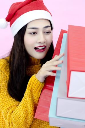 A beautiful Asian woman wearing a red Santa hat with a shopping bag.の写真素材
