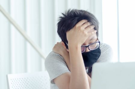 Asian Men Wearing Glasses Wearing a black mask Is working.A sick man sitting at work.In the white office there was a man in there.の写真素材