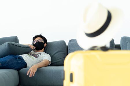 Asian Men Wearing Glasses Wearing a black mask Sleeping on the gray sofa in his room.A sick man is sleeping.On the gray sofa someone was resting.の写真素材
