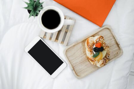 On a white background there is coffee, smartphones, bread. With an orange book.Do not focus on the object.の写真素材
