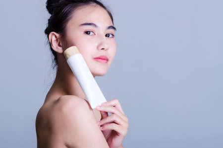 Asian woman Beautiful with a charming smile with white skin White cream jar in her hand. isolated on white background.cosmetic concept for beautyの写真素材