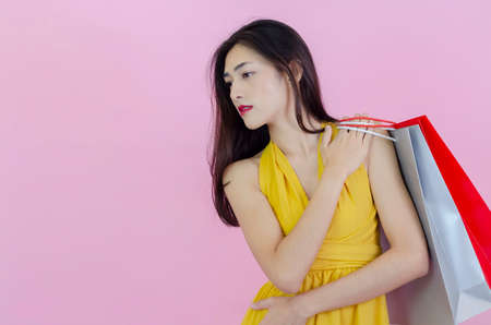 Asian women wear black clothes. Carrying a shopping bag in green, gray, red With pink background