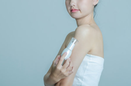 Beautiful young asian woman applying cosmetic cream on her arm.の写真素材