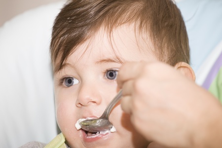 Mother feeding her happy little cute boyの写真素材
