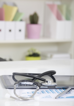 Doctor office table desk and black chair with stethoscope  and white paperの写真素材
