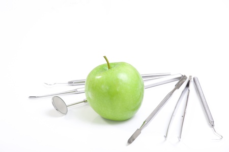 Green apple and dental tools isolated on whiteの写真素材