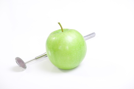 Green apple and dental tools isolated on whiteの写真素材