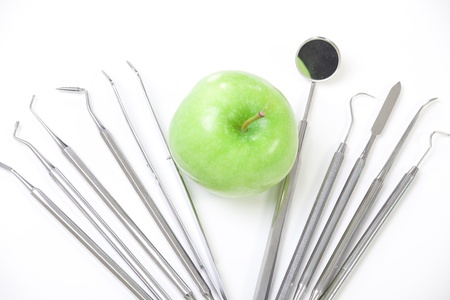 Green apple and dental tools isolated on whiteの写真素材