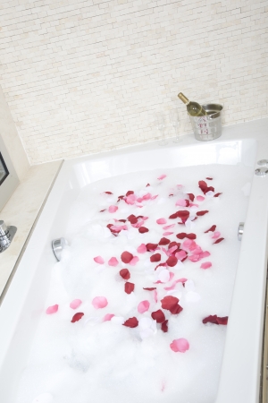A relaxing bath with rose petals ,wine and glassessの写真素材