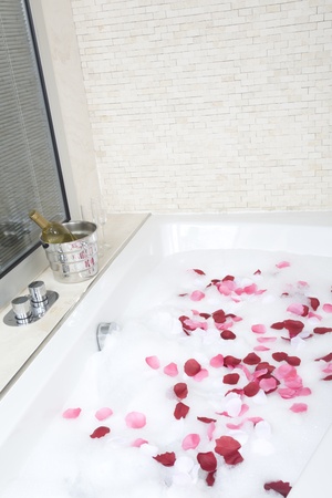 A relaxing bath with rose petals ,wine and glassessの写真素材