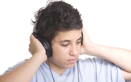 Portrait of a sweet young boy listening to music on headphones against white background