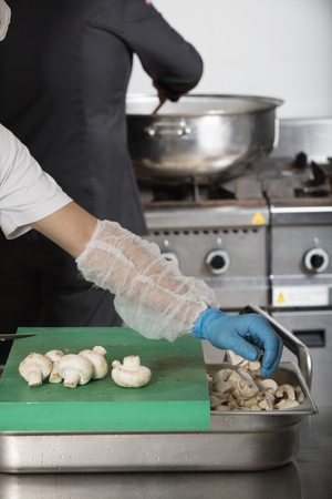 chef preparing food and cutting mushrooms in a restaurant kitchenの写真素材