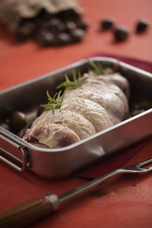 raw turkey in tray over red background with chestnutの写真素材