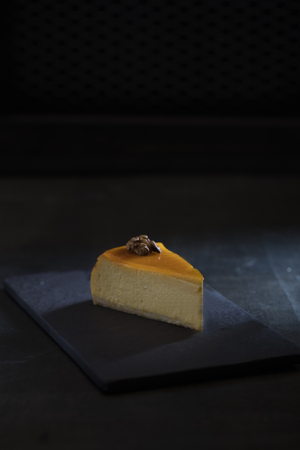 one slice of pumpkin cheesecake over dark backgroundの写真素材
