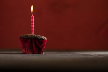 Chocolate birthday cupcake with candle over dark backgroundの写真素材