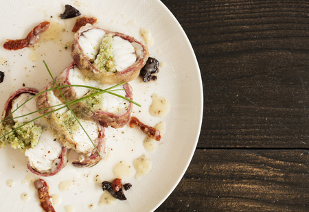 cod fish wrapped in bacon on black backgroundの写真素材