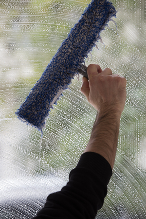 A soapy window with a squeegee cleaning the glass