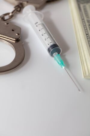 money and syringe and handcuffs on white background.の写真素材