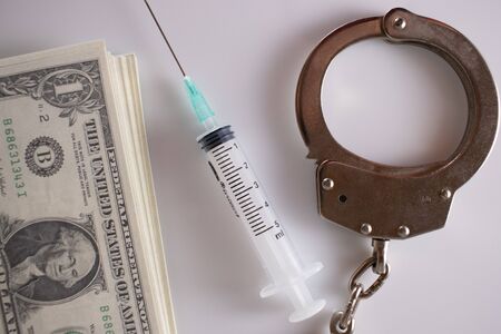 money and syringe and handcuffs on white background.