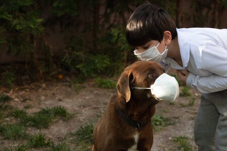 boy wearing a protective mask with a dog outdoors because of the corona virus pandemic covid-19の写真素材