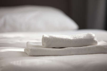 White clean towels stacked on the hotel bed. High quality photoの写真素材