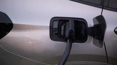 Power cable pump plug in charging power to electric vehicle EV car with modern technology UI control information display, car fueling station connected power cable alternative sustainable eco energy. High quality photoの写真素材