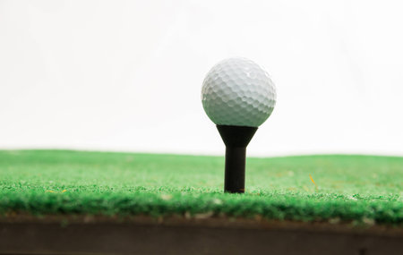 White golf ball on green grass isolated on white with shadow horizontal background with selective focus.の写真素材