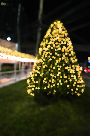 Abstract blurred decorated christmas tree background with golden lights glowing bokeh at night festival.の写真素材
