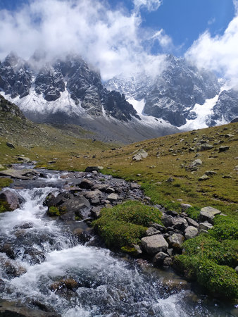 Mountain landscape with a stream and snow-capped peaks in the backgroundの写真素材