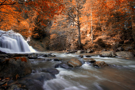 Autumn landscape with waterfall and rocks in the forest, long exposure